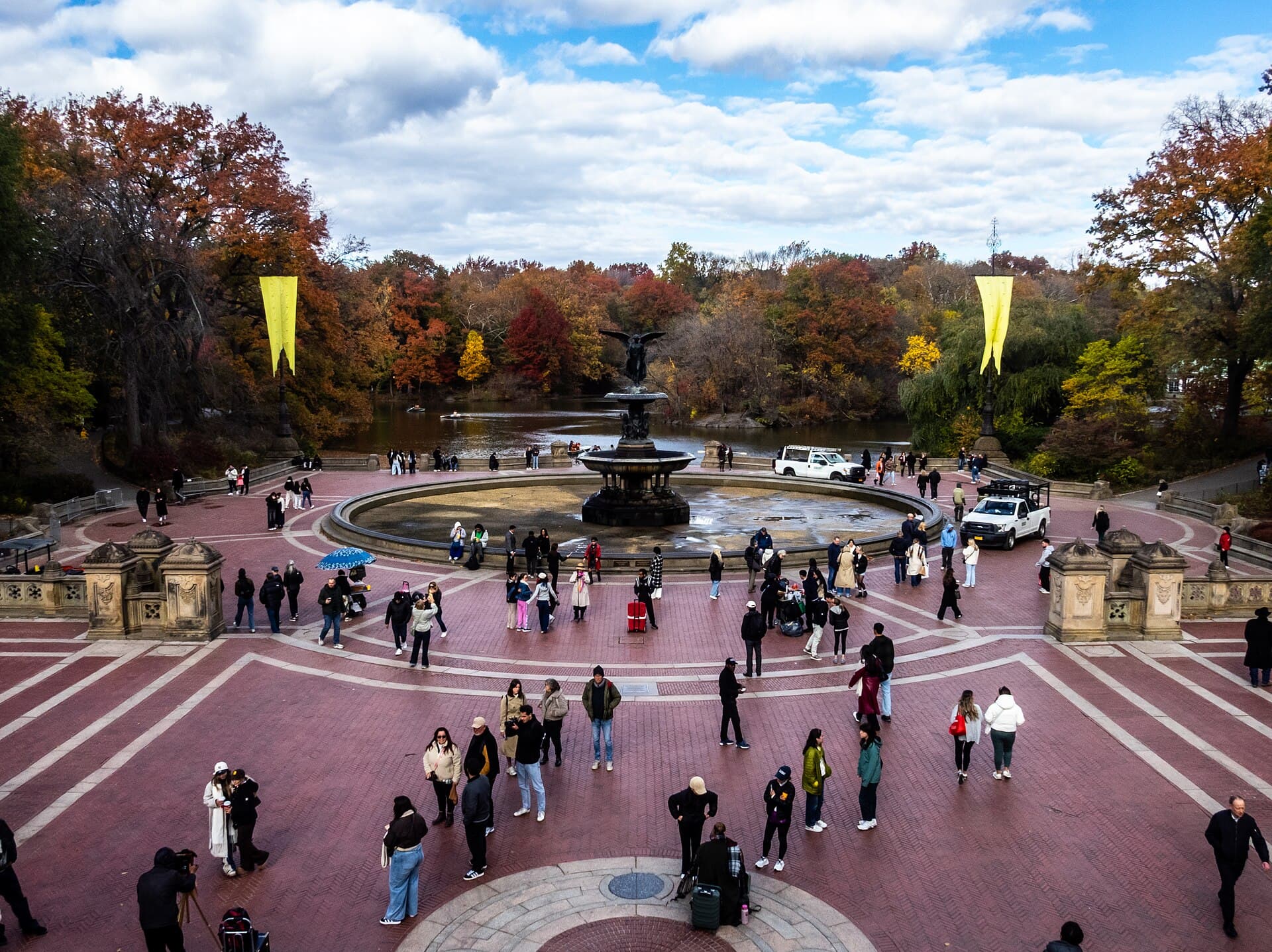 Visitors at Bethesda Fountain in Central Park with autumn foliage and rowboats on the lake